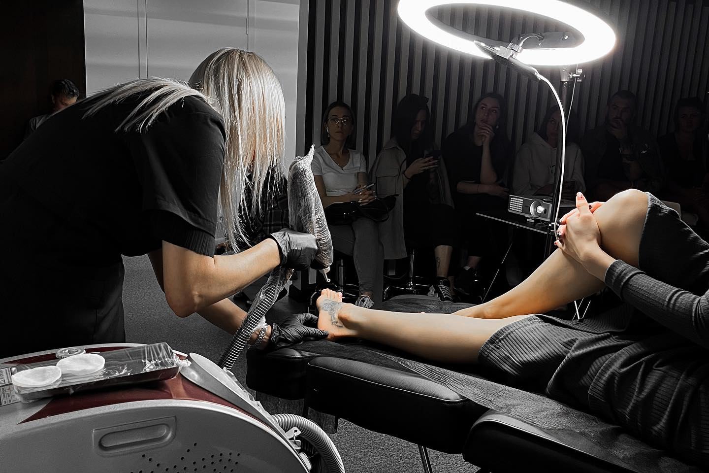 specialistas atlieka tatuiruotės šviesinimo rėmoveriu procedūrą